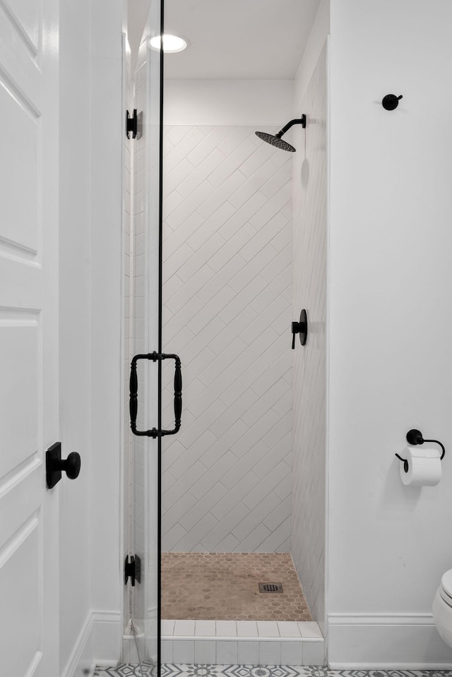 full bath with toilet, baseboards, and a shower stall