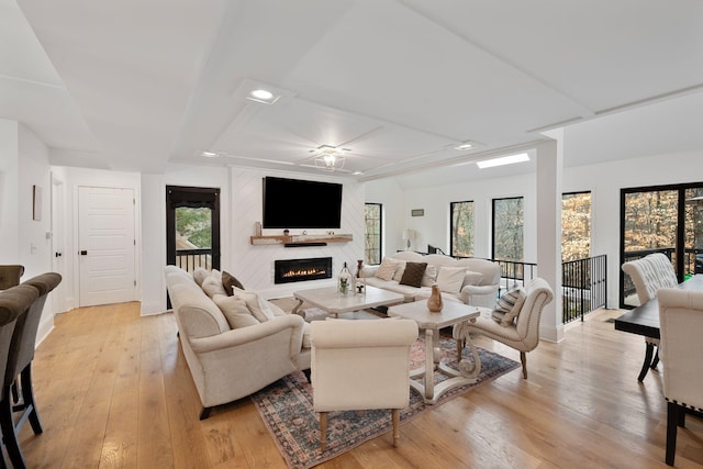 living room featuring light wood-type flooring, a large fireplace, and ceiling fan