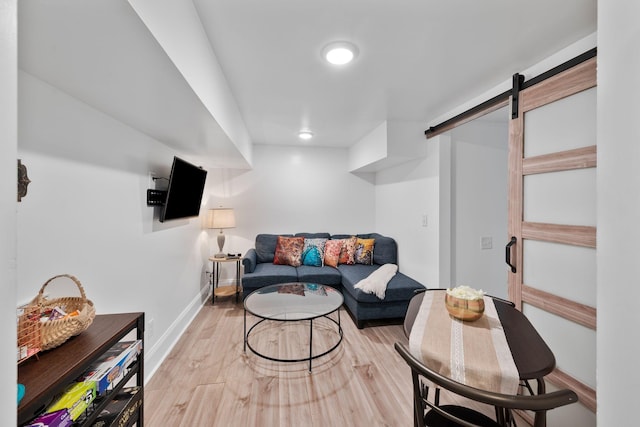 living area featuring baseboards, a barn door, and wood finished floors