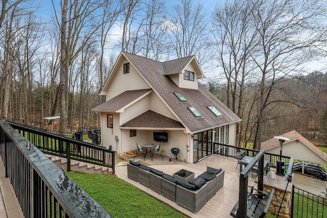 rear view of property with fence, a fire pit, a deck, and roof with shingles