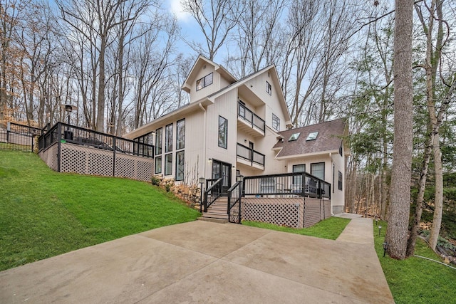 rear view of property featuring roof with shingles, a deck, and a yard