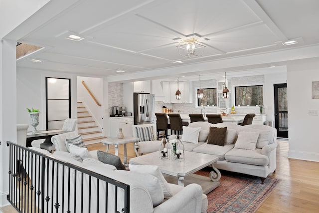 living area with light wood finished floors, baseboards, and stairway