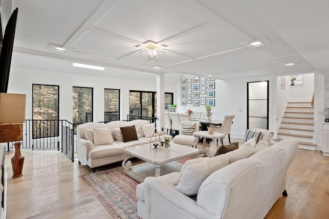 living area with a notable chandelier, light wood-style flooring, and stairway