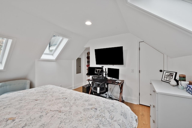 bedroom featuring multiple windows, vaulted ceiling with skylight, electric panel, and light wood finished floors