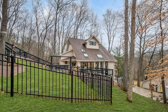 view of front facade with a shingled roof, a front yard, and a fenced front yard