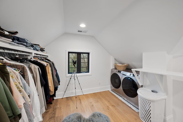 clothes washing area with visible vents, baseboards, laundry area, washer and dryer, and wood-type flooring