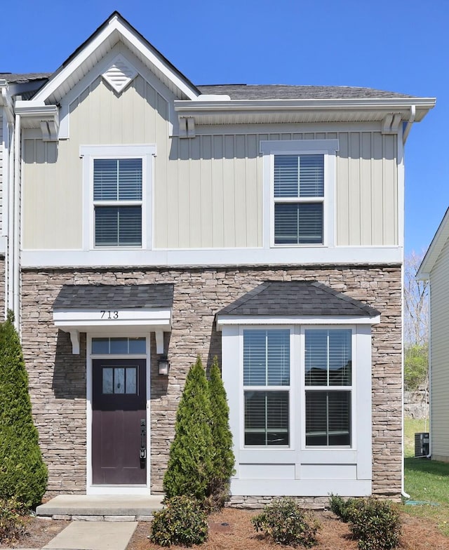 view of front of property with stone siding, central air condition unit, and board and batten siding