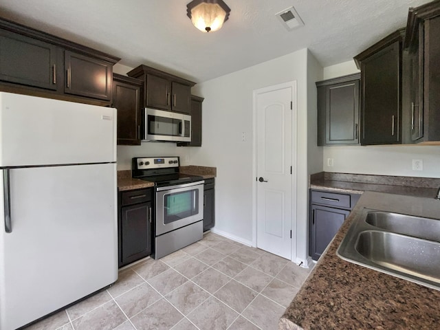 851 Salem Rd, Clarksville, TN 37040 - kitchen with stainless steel appliances, a sink, light tile patterned flooring, dark countertops, and dark brown cabinetry