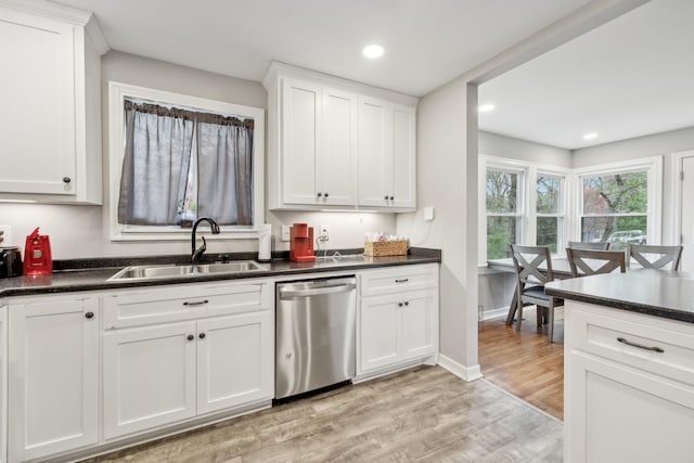 kitchen with a sink, dark countertops, light wood finished floors, and stainless steel dishwasher