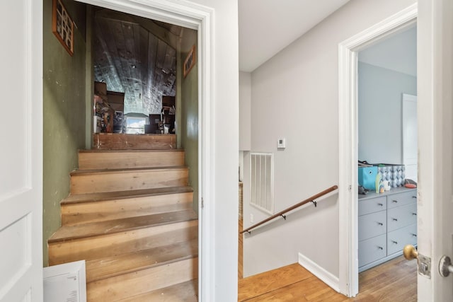 stairway featuring visible vents and wood finished floors
