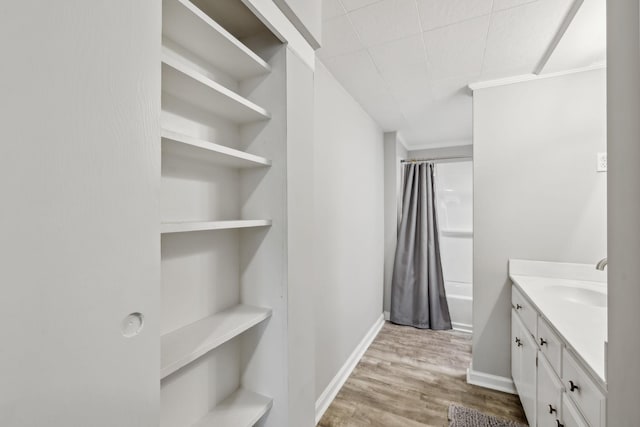full bath with baseboards, wood finished floors, shower / tub combo, and vanity