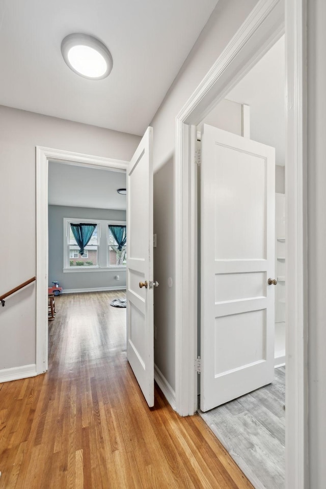 hallway featuring baseboards and light wood finished floors