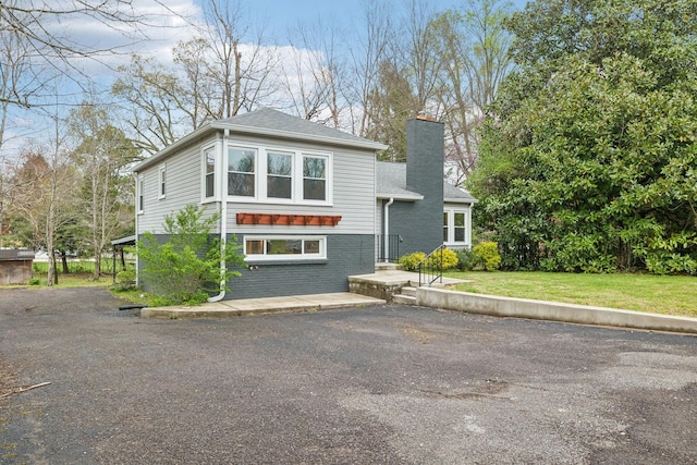 view of front facade with a chimney, a front lawn, and brick siding
