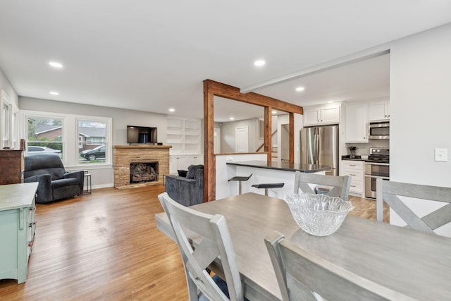 dining area with light wood-style flooring, baseboards, a fireplace, and recessed lighting