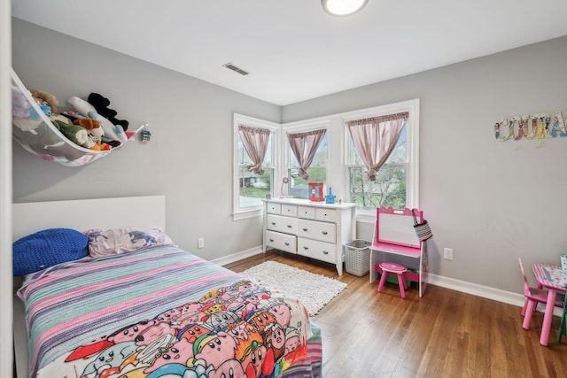bedroom featuring visible vents, baseboards, and wood finished floors