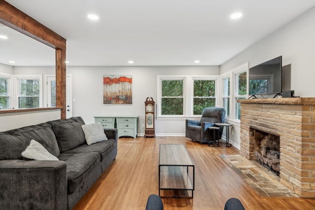 living room with recessed lighting, a stone fireplace, baseboards, and wood finished floors