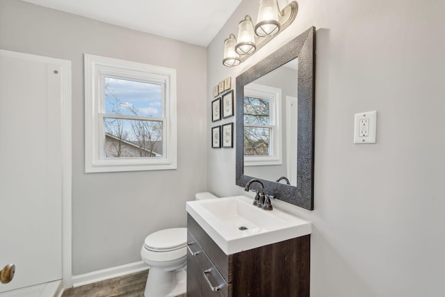 half bathroom with baseboards, toilet, vanity, and wood finished floors