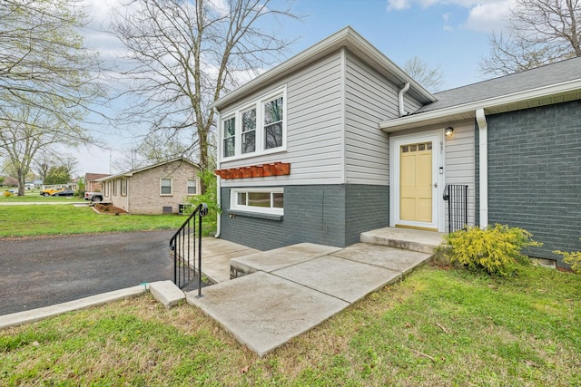 property entrance with brick siding and a yard