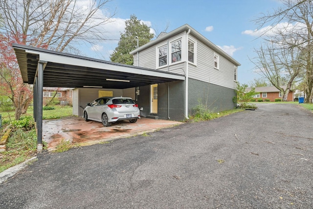 exterior space featuring driveway, concrete block siding, and a carport