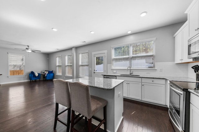 2037 Hamilton Hill Dr, Antioch, TN 37013 - kitchen with plenty of natural light, stainless steel appliances, a breakfast bar, a sink, and dark wood-style flooring