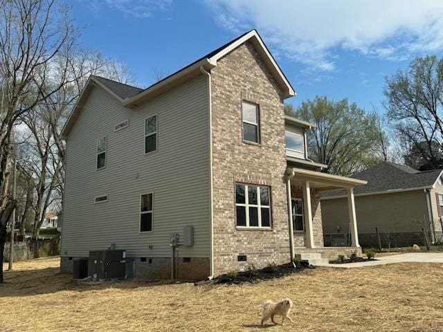 view of home's exterior with crawl space, cooling unit, a porch, and brick siding