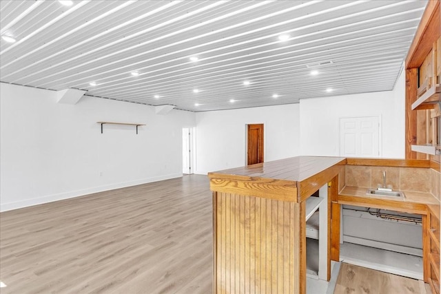 interior space featuring a sink, baseboards, and light wood-type flooring