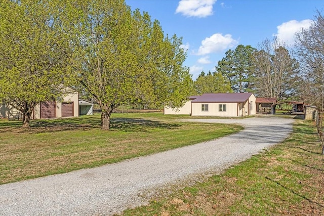 view of front facade featuring a front lawn, a detached carport, and gravel driveway