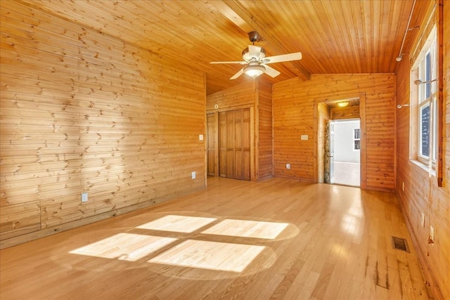 spare room featuring lofted ceiling, wooden ceiling, wooden walls, visible vents, and wood finished floors