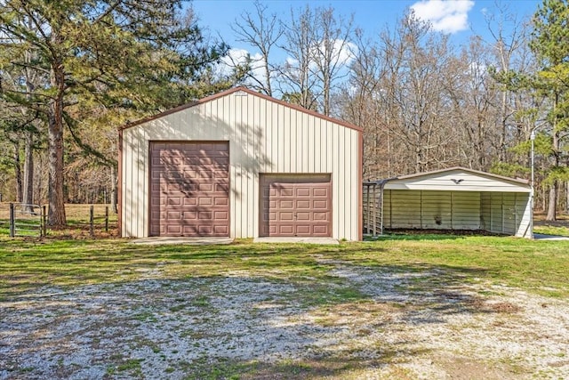 view of outdoor structure with driveway, an outbuilding, and fence