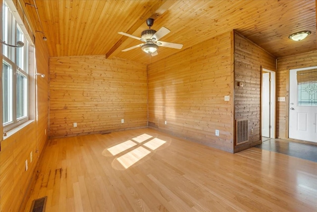 empty room featuring a wealth of natural light, visible vents, and wood finished floors