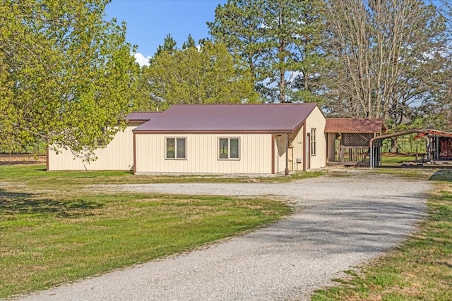 view of front of house with driveway, a front lawn, a detached carport, and metal roof