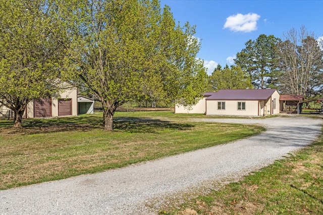 view of front facade with a front yard, gravel driveway, and an outdoor structure