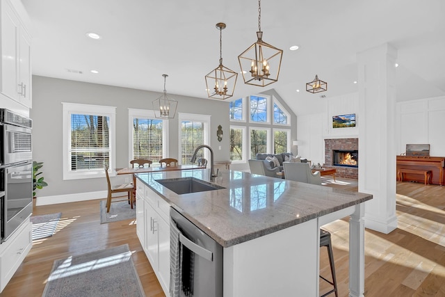 1017 Cliff View Dr N, Kingston Springs, TN 37082 - kitchen with an inviting chandelier, light wood-style floors, a brick fireplace, appliances with stainless steel finishes, and a sink
