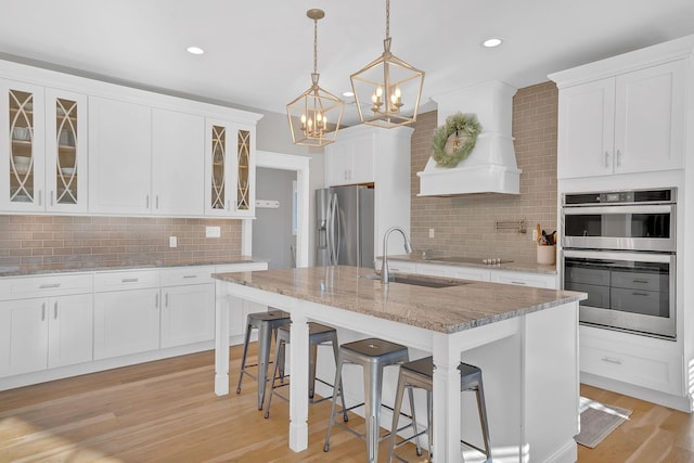 1017 Cliff View Dr N, Kingston Springs, TN 37082 - kitchen featuring light wood-style floors, glass insert cabinets, a chandelier, appliances with stainless steel finishes, and a sink