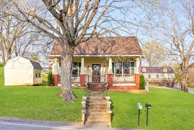 view of front of home featuring a storage shed, a porch, brick siding, a shingled roof, and a front yard