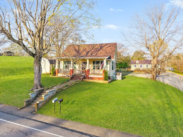 view of front of property with a storage shed, a front lawn, a shingled roof, covered porch, and an outbuilding