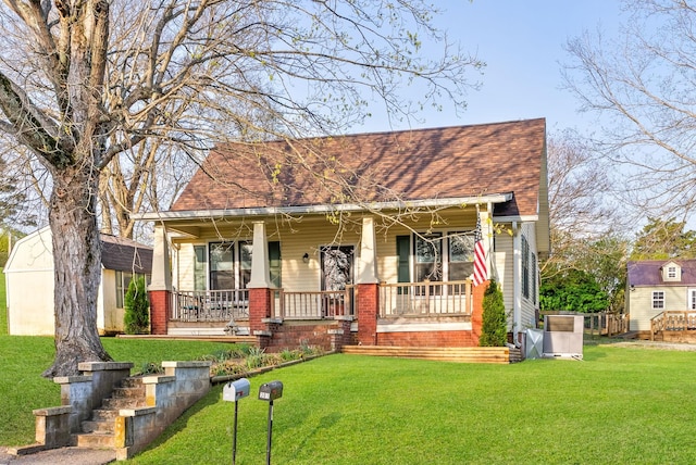 view of front of house featuring brick siding, roof with shingles, a front yard, and covered porch
