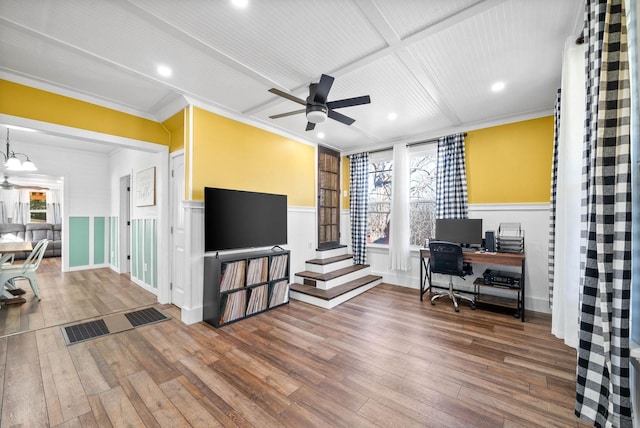 office space featuring wood-type flooring, crown molding, a wainscoted wall, and ceiling fan with notable chandelier