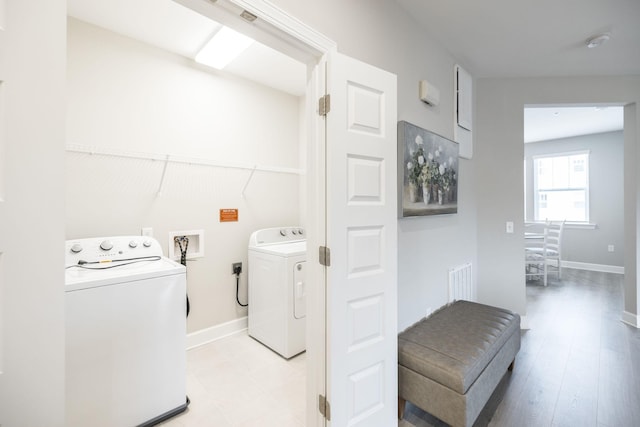 laundry room with washing machine and clothes dryer, visible vents, light wood-style flooring, and baseboards