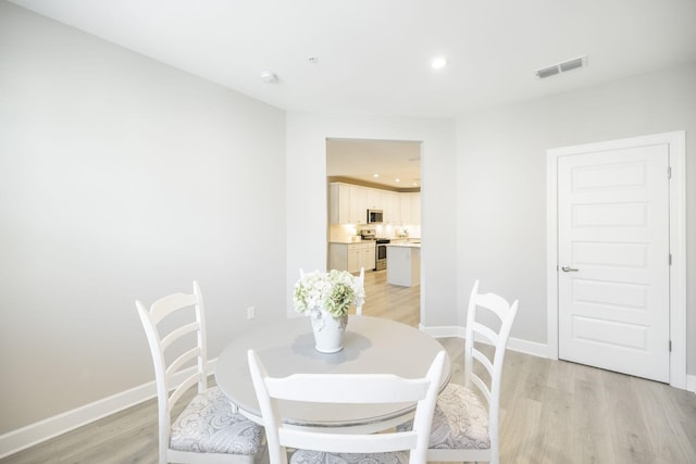 dining room with baseboards, light wood-style flooring, and visible vents