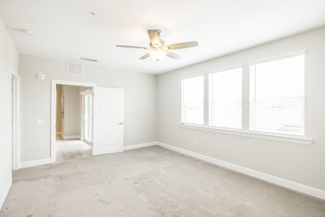 unfurnished room featuring baseboards, ceiling fan, visible vents, and light colored carpet