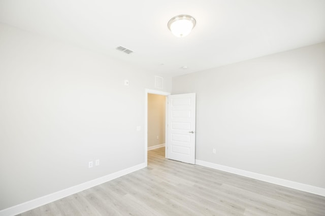 empty room featuring baseboards, visible vents, and light wood finished floors
