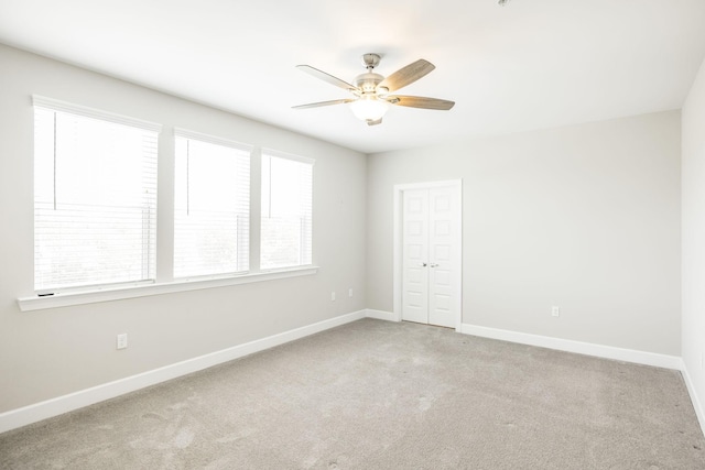 spare room featuring baseboards, ceiling fan, and light colored carpet