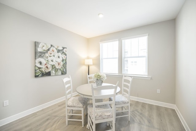 dining area with baseboards and light wood-style flooring