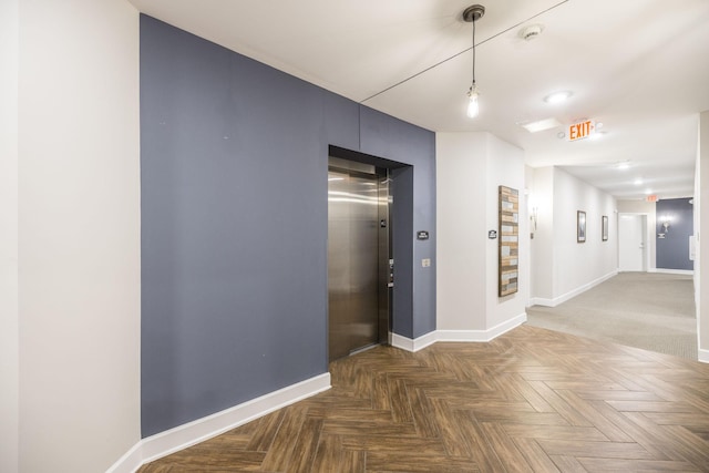 hallway featuring elevator and baseboards