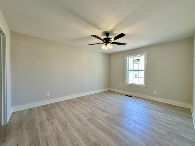 spare room featuring light wood finished floors, baseboards, and a ceiling fan