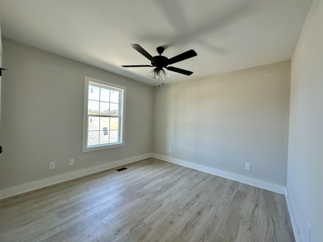 empty room with baseboards, light wood-style flooring, visible vents, and a ceiling fan