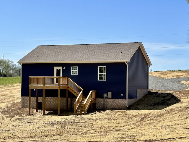 back of house featuring a shingled roof, a wooden deck, and stairway