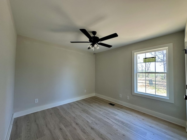 spare room with baseboards, visible vents, wood finished floors, and a ceiling fan