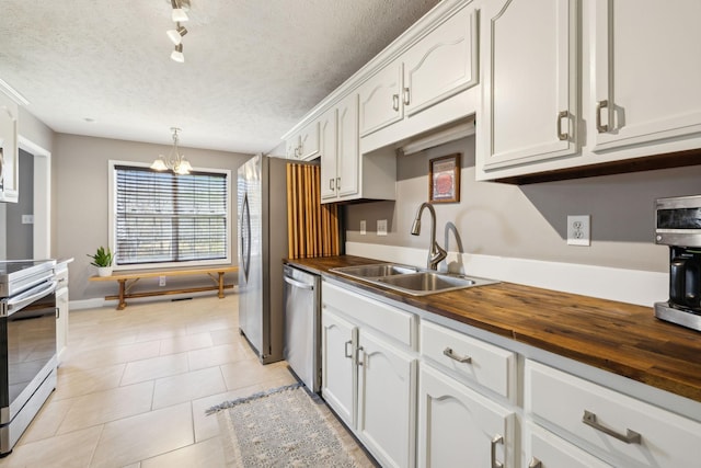 3648 S Jot Dr, Clarksville, TN 37040 - kitchen with a textured ceiling, wood counters, stainless steel appliances, a sink, and light tile patterned floors